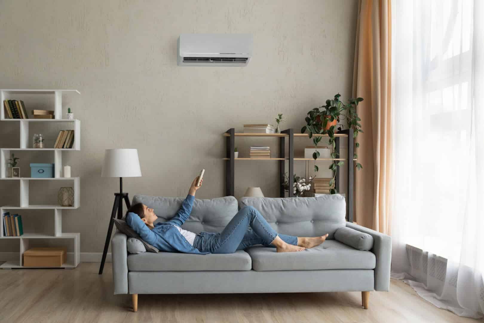 Woman comfortably adjusting her AC on a sofa