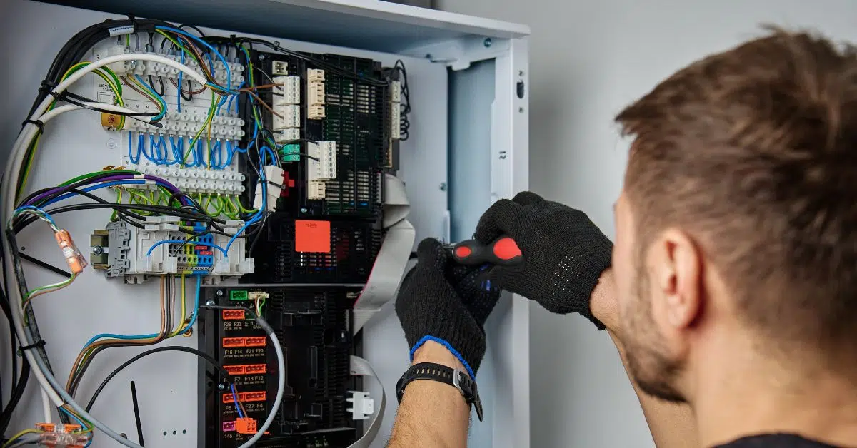 Licensed electrician inspecting a home electrical panel for summer safety in Norwood MA